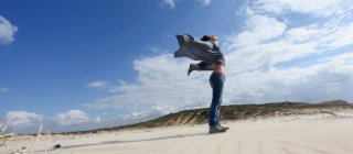 Frau steht am windigen Strand — Stockfoto