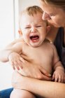 Mãe segurando chorando bebê menina — Fotografia de Stock
