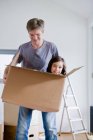 Father carrying daughter in box — Stock Photo