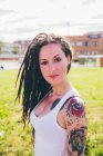 Portrait of tattooed young woman in urban park — Stock Photo