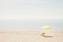 Lawn chair and umbrella on beach — Stock Photo