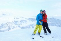 Skiers hugging on snowy mountaintop — Stock Photo