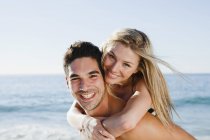Homem carregando namorada na praia — Fotografia de Stock