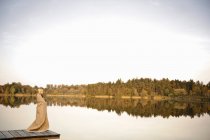 Giovane donna in piedi sul molo, godendo — Foto stock