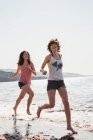 Женщины бегут волнами по пляжу — стоковое фото