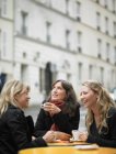 Женщины пьют кофе на тротуаре кафе — стоковое фото