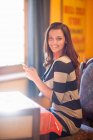 Молода жінка в кафе за допомогою мобільного телефону — стокове фото