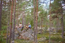 Familia sentada en rocas en el bosque comiendo picnic - foto de stock