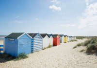 Cabañas de colores brillantes en la playa bajo el cielo azul - foto de stock