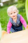 Toddler girl climbing slide in backyard — Stock Photo