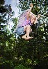 Menina vestindo asas e pulando na floresta — Fotografia de Stock