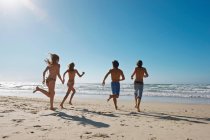 Young people running towards sea — Stock Photo