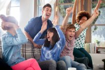 Group of friends watching tv cheering — Stock Photo