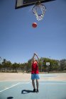 Young male basketball player throwing ball toward basketball hoop — Stock Photo