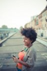 Mujer joven eligiendo la música desde el teléfono inteligente en la ciudad - foto de stock
