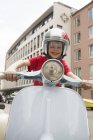 Porträt eines zehnjährigen Jungen, der vorgibt, Motorroller auf der Stadtstraße zu fahren — Stockfoto