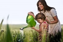 Woman helping child with watering can — Stock Photo