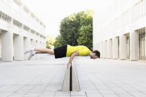 Jeune homme équilibrant horizontalement sur le diviseur — Photo de stock