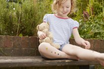 Chica pegando estrellas en las piernas en el asiento del jardín - foto de stock