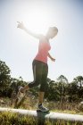 Femme jogger équilibrage sur pipe dans rétro-éclairé à l'extérieur — Photo de stock