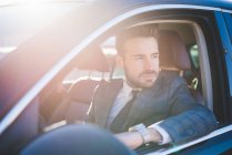 Young businessman looking out from car window — Stock Photo