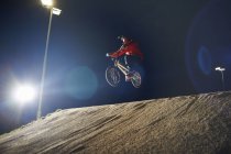 BMX-ciclista pula sua bicicleta à noite — Fotografia de Stock