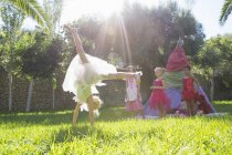 Дівчата спостерігають за другом у казковому костюмі роблять колесо в саду — стокове фото