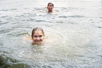 Adolescente y hermana nadando en el lago rural - foto de stock
