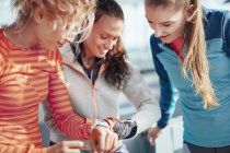 Três corredoras femininas verificando o tempo em smartwatches — Fotografia de Stock