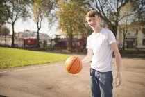 Портрет усміхненого юного баскетболіста, який тримає баскетбол — стокове фото