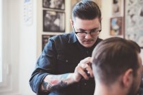 Barbiere usando le tosatrici sui capelli dei clienti nel negozio di barbiere — Foto stock