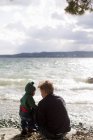 Père et petite fille accroupis au bord du lac, lac Starnberg, Bavière, Allemagne — Photo de stock