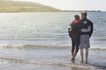 Mittleres erwachsenes Paar mit Armen umeinander am Strand, loch eishort, isle of skye, hebrides, scotland — Stockfoto