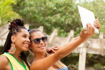 Mujeres tomando selfie usando tableta digital, Rio de Janeiro, Brasil - foto de stock