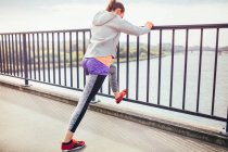 Corridore femminile facendo esercizio di riscaldamento sul ponte pedonale — Foto stock