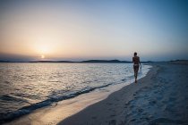 Rückansicht einer jungen Frau, die mit Bikini-Oberteil am Strand spaziert, cagliari, sardinien, italien — Stockfoto