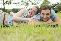 Couple adulte moyen allongé sur l'herbe — Photo de stock