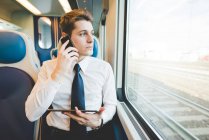 Retrato de un joven hombre de negocios viajero usando tableta digital en tren . - foto de stock