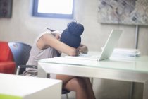 Büroangestellte lehnt gestresst und aufgebracht am Schreibtisch — Stockfoto