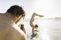Sur la vue d'épaule de l'homme photographiant petite amie sur la plage, Cape Town, Afrique du Sud — Photo de stock