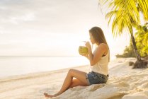 Молода жінка, пити свіже молоко кокосового Анда пляж, провінція Бохол, Філіппіни — стокове фото