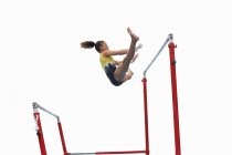 Young gymnast performing on uneven bars — Stock Photo