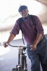 Senior man pushing bicycle through city underpass — Stock Photo