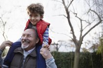 Älterer Mann trägt Enkel lächelnd auf den Schultern — Stockfoto