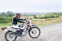 Mid adulte femme motocycliste équitation sur la piste de terre — Photo de stock