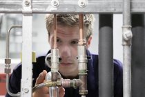 Männlicher Ingenieur hält industrielle Versorgungsleitungen in Fabrik aufrecht — Stockfoto