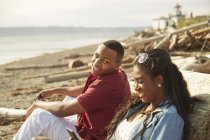 Молода пара сидить разом на пляжі посміхаючись — стокове фото