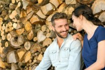 Jovem casal sentado na frente de madeira picada cara a cara sorrindo — Fotografia de Stock