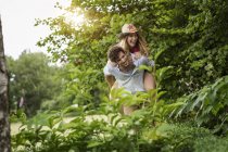 Junger Mann gibt Freundin ein Huckepack zurück im Garten — Stockfoto