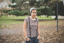 Retrato de adolescente de pie en el parque con las manos en los bolsillos - foto de stock